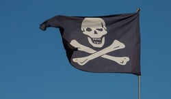 jolly roger. pirate flag.Against the background of blue sky.