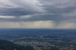 Particular view of a completely cloudy sky and the rain falling above the land, looking south east in the center of the plain of Friuli Venezia Giulia region, Italy