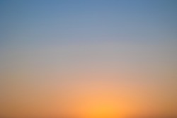 abstract colorful background with shades between light-blue and orange, blurred sky at sundown