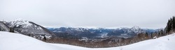 extreme wide angle view of a mountain landscape around Tolmezzo during winter season. white snowy ground and grey cloudy sky. Friuli Venezia Giulia region, Italy