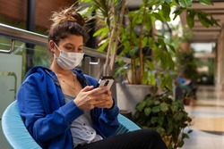 woman with mask, blue sweater and cell phone in Medellin, Colombia.