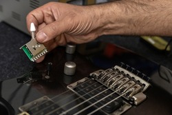 Latin American luthier holds in his hand the new switch of an electric guitar that will change. Unrecognizable person. Concept repair, instrument, guitar