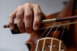 Close-up of the hand holding the bow at the heel and placed correctly on the G string on the cello. Concept orchestra instrument and music student.