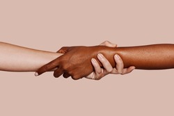 Close up multiracial woman couple with black and caucasian hands holding each other wrist in tolerance unity love and anti racism concept