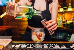 Female bartender preparing cocktail at the night club. Barwoman preparing gintonic with balloon cup. Alcoholic drink, Beverage.