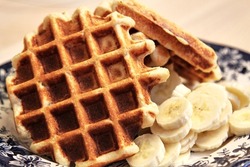 Homemade Belgium waffles served with banana slices. Selective focus. High quality photo