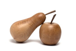 Close up of a hardwood wood turned pear leaning on an artificial apples on white background