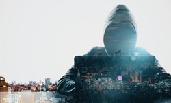 Hacker at desktop using laptop on white glowing night city background. Technology and theft concept. Double exposure 