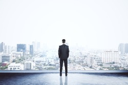 Businessman standing on building. City background with copy space. Success and vision concept