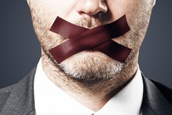 Close up of taped caucasian businessman mouth. Silence and speech censorship concept