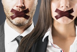 Close up of european man and businesswoman with taped mouthes. Silence and speech censorship concept
