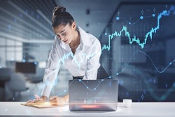 Financial analyzing and market forecast concept with young woman working with data, making notes in notebook and growing digital forex chart diagram and candlestick, double exposure