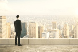 Businessman on the top of builng and looking at the city