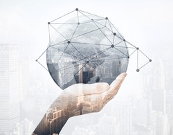 Close up of hand holding abstract globe with connections on city background. Global business concept. Double exposure