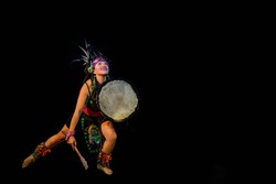 young woman Teotihuacana, Xicalanca - Toltec in black background, with traditional dress dance with a trappings with feathers and drum