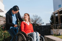 Happy young latin woman in wheelchair and her friend having fun outdoors in Mexico