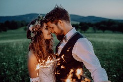 Beautiful bride and groom with sparklers on a meadow.