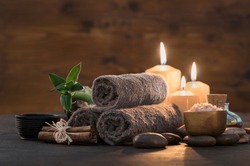 Brown towels with bamboo and candles for relax spa massage and body treatment. Composition with candles, spa stones and salt on wooden background. Spa and wellness setting ready for beauty treatment. 