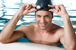 Happy smiling athletic swimmer wearing glasses at swimmingpool
