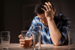alcoholism, alcohol addiction and people concept - male alcoholic drinking beer from glass at night