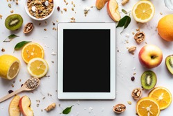 Healthy super food and technology background, digital tablet computer apps for cooking diet nutrition plan, fresh fruit granola seeds on white organic table, health care detox, top view mockup screen