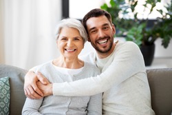 family, generation and people concept - happy smiling senior mother with adult son hugging at home