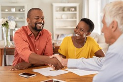 Mature black husband shaking hands with senior agent on taking loan. Happy african couple sealing with handshake a contract with financial advisor for investment. Man making sale purchase deal.
