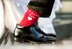 Groom's funny feet with love sign on red socks.