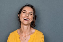 Portrait of mature woman laughing against grey background. Successful middle aged woman in casual with toothy smile looking at camera. Cheerful happy beautiful latin lady smiling with copy space.