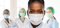 health, medicine and pandemic concept - close up of african american female doctor or scientist in protective mask over medical workers at hospital on background