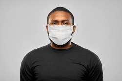 health, pandemic and safety concept - african american young man wearing face protective medical mask for protection from virus disease over grey background