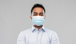 business, healthcare and people concept - portrait of indian man in shirt wearing face medical mask for protection from virus disease over grey background
