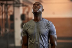 Fit young African American man standing with his eyes closed and sweating after a gym workout