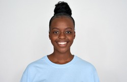 Happy young african american woman wear blue tshirt look at camera isolated on grey background. Positive pretty black ethnic girl with healthy white teeth, dental smiling headshot portrait, close up.