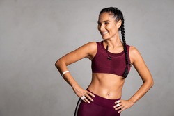 Happy beautiful fit woman laughing and looking away after gym exercise isolated on grey background. Middle aged woman wearing sports bra on gray wall with copy space. Carefree fitness girl resting.