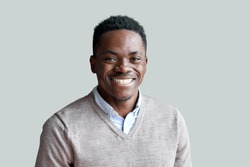 Smiling cheerful young adult african american ethnicity man looking at camera standing at home office background. Happy confident black guy posing for headshot face front close up portrait.