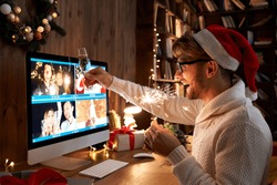 Young man wearing Christmas hat drinking champagne holding sparkler talking to friends on virtual zoom video call celebrate Happy New Year party in distance online conference chat on computer at home.