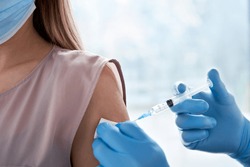 Male doctor holding syringe making covid 19 vaccination injection dose in shoulder of female patient. Flu influenza vaccine clinical trials concept, corona virus treatment side effect, inoculation. 