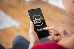 Woman taking benefit of cash back using smart phone, shopping and money refund concept. Close up hand holding smartphone with button to get started the cashback. 