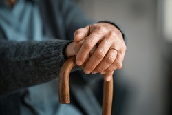 Close up of senior disabled woman hands holding walking stick. Detail of old woman hands holding handle of cane. Old lady holding walking stick.