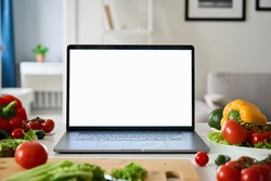 Laptop computer with mockup white screen on vegetarian healthy food vegetable background. Online grocery shopping delivery app ads concept, cook book diet plan nutrition recipes, close up view.