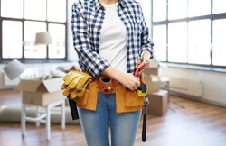 moving, repair and people concept - woman or builder with pliers and working tools on belt over new home background