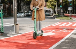 traffic, city transport and people concept - woman riding electric scooter along red bike lane with signs of bicycles and two way arrows on street