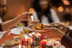 holidays, eating and celebration concept - close up of friends having christmas dinner at home and sharing food