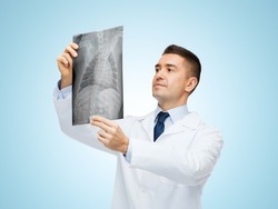 medicine, pet and healthcare concept - middle aged male veterinarian doctor looking at animal's x-ray over blue background