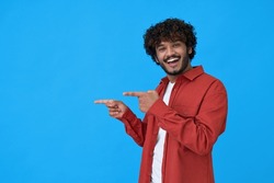 Happy excited young indian man looking at camera pointing aside with fingers hand gesture at copy space advertising new promotion, presenting sale offer standing isolated on blue background.