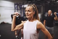 Fit mature woman in sportswear lifting a dumbbell during a strength training session at the gym