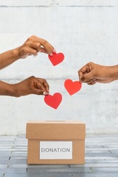 charity, love and valentine's day concept - close up of hands putting red hearts into donation box over urban steet background