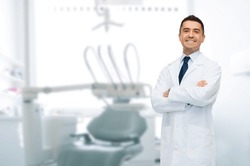 healthcare, profession, stomatology and medicine concept - smiling male middle aged dentist over medical office background
