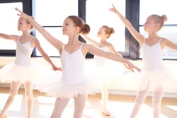 Choreographed dance by a group of graceful pretty young ballerinas practicing during class at a classical ballet school